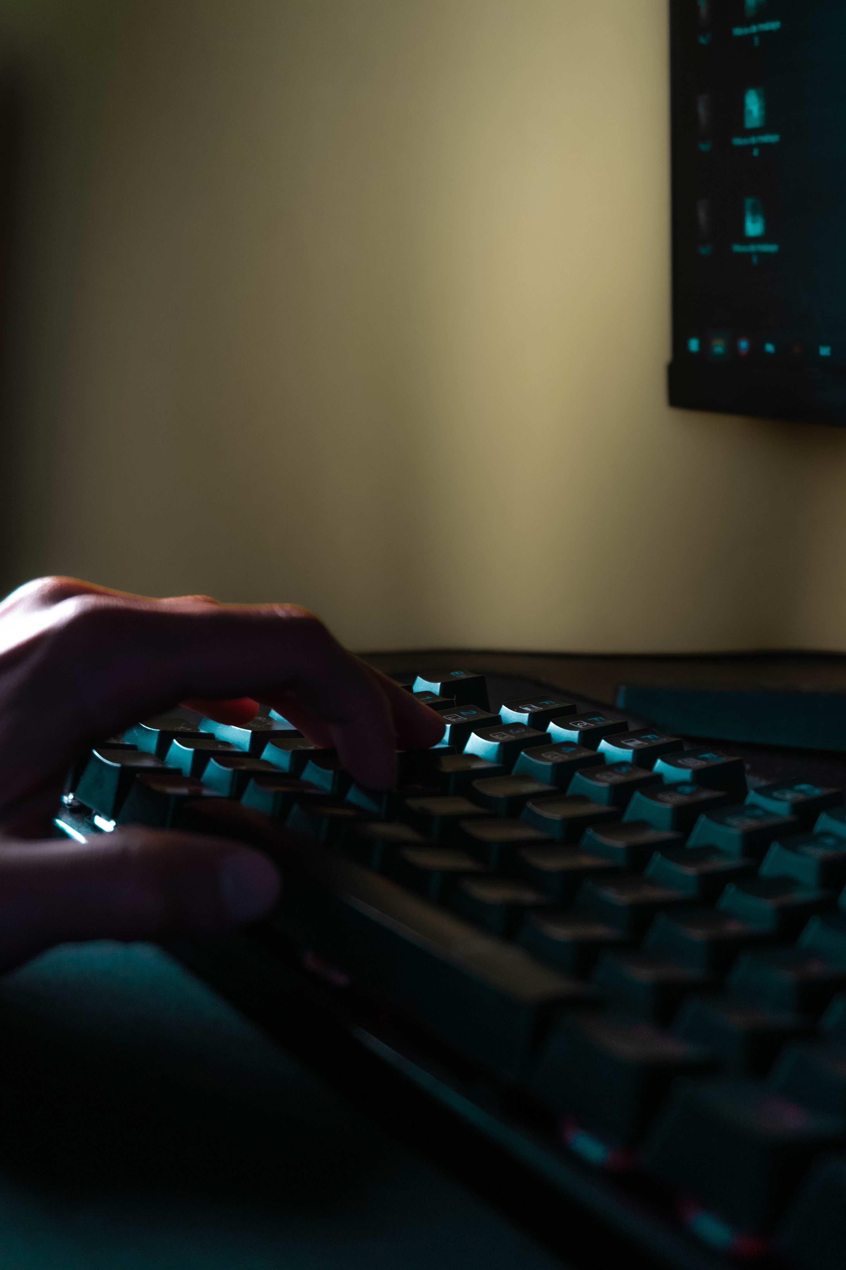Hands typing on a laptop keyboard with screen glow in a dim room